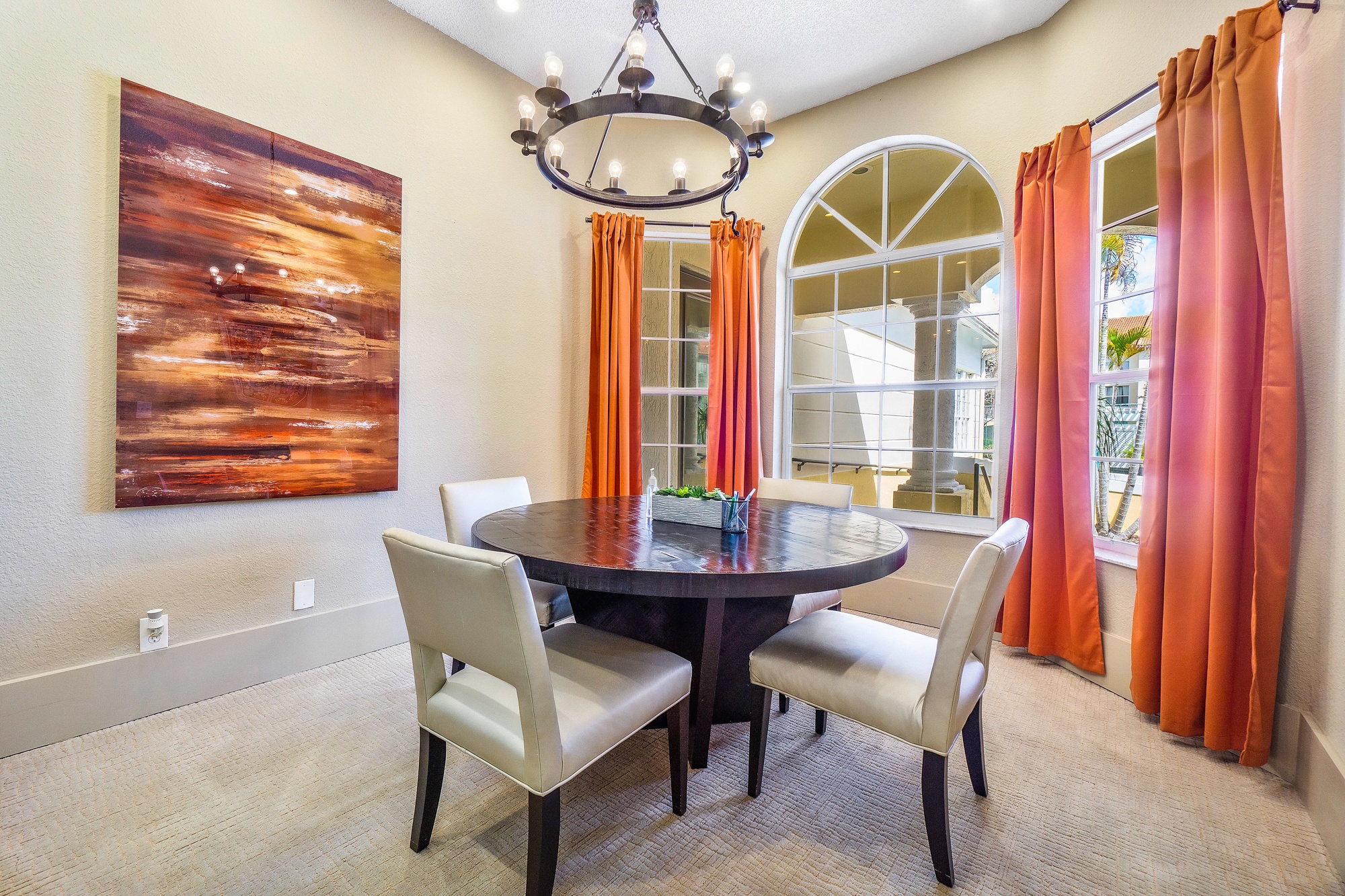 A dining room with a table, chairs and a painting on the wall.